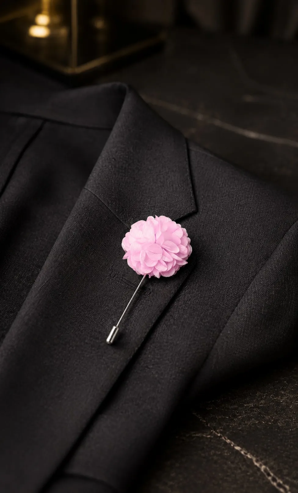 Pino de lapela em flor rosa, preso à lapela de um paletó preto